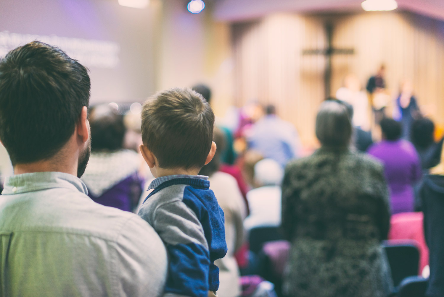 man and child worshipping with congregation